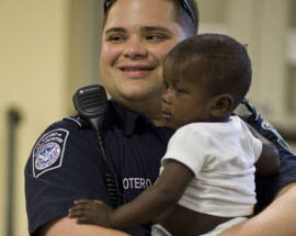 DHS Customs and Border Protection officer holding Haitian child