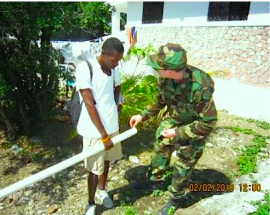 LCDR Russell explains the assembly of a well drop-pipe at a Grand Goave IDP camp