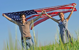 A man and woman standing in a field holding up an American flag