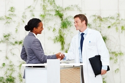 Man in white doctor coat shaking a woman