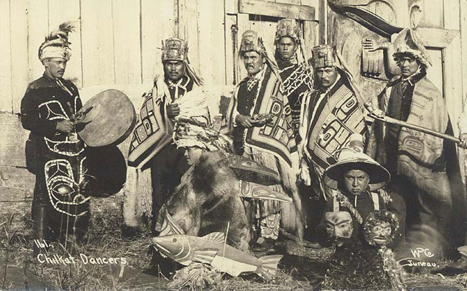 A group of Native Americans holding instruments and masks.