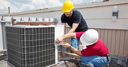 Two men working on an air conditioner