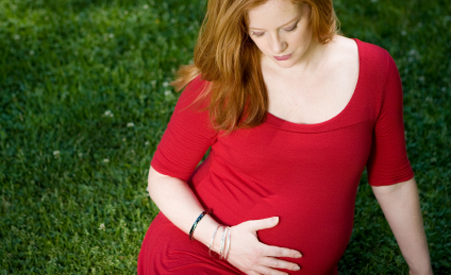 pregnant woman sitting on grassy field