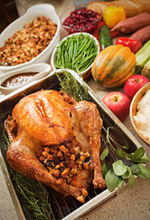 A thanksgiving meal of turkey, vegetables and fruit is presented.