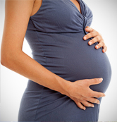 A pregnant woman holds her stomach.