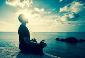 A man meditates at sunset.