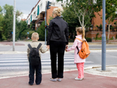 A mom holds her son and daughter’s hands.