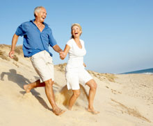 Photo of an older couple running down a sand dune