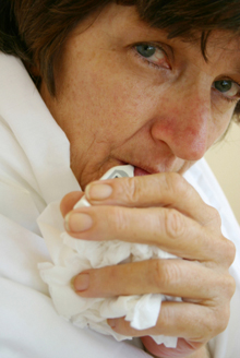 Photo of a woman holding a crumpled tissue.