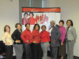 Eight women pose in front of the Memphis Champions Heart Truth display.