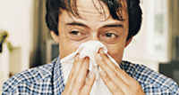 A man blowing his nose into a tissue
