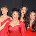 9 celebrity women from The Heart Truth's 2007 Fashion Show wearing designer red dresses pose together backstage after the show.
