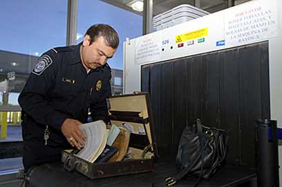 A CBP officer checks an individual's luggage after being x-rayed.