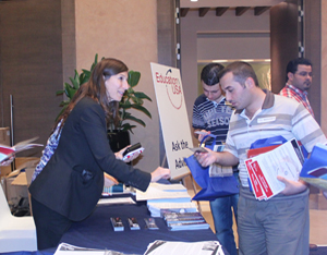 People stand and talk and look at Education fair table (Photo by State Dept.)