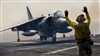 A crewman directs the pilot of a AV-8B Harrier as it touches down on the flight deck of the USS Kearsarge 