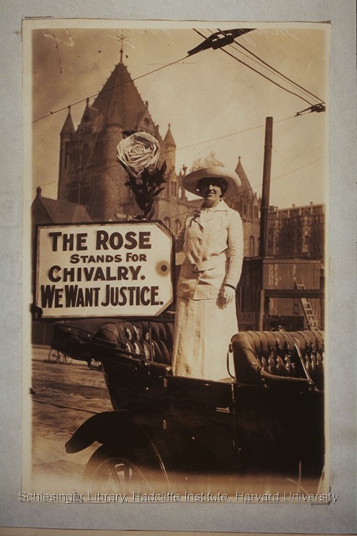  Woman with a sign reading “The Rose Stands For Chivalry. We Want Justice.” Trinity Church, Boston, 1914.