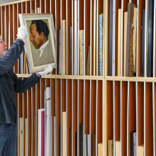 Man with taking a portrait from a rack of many artworks