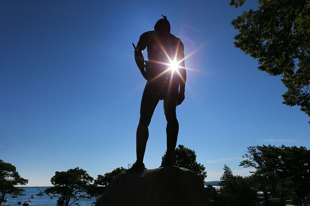 Sun shines through the statue of Wampanoag Indian chief Massasoit that stands atop a hill overlooking Plymouth Rock in Plymouth, Mass., on Aug. 27, 2015.