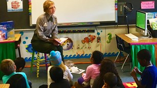 Park Ranger in a classroom reading to young students seated on the floor