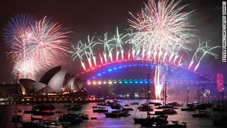 New Year&#39;s Eve fireworks erupt over Sydney&#39;s iconic Harbour Bridge and Opera House (L) during the fireworks show on January 1, 2020.