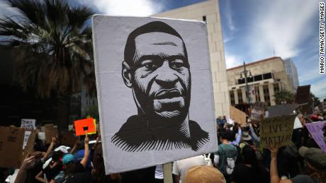 A protester holds a sign with an image of George Floyd during a peaceful demonstration over George Floyd&#39;s death outside LAPD headquarters on June 2, 2020 in Los Angeles, California. California Governor Gavin Newsom has deployed National Guard troops to Los Angeles County to curb unrest which occurred amid some demonstrations. Former Minneapolis police officer Derek Chauvin was taken into custody for Floyd&#39;s death and charged with third-degree murder. (Photo by Mario Tama/Getty Images)