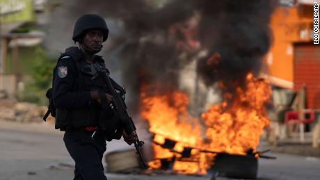 A policeman walks past a burning barricade during a protest after security forces blocked the access to the house of the former president Henri Konan Bedie, in Abidjan, Ivory Coast, Tuesday, Nov. 3, 2020. Ivory Coast&#39;s electoral commission said Tuesday that President Alassane Ouattara had overwhelmingly won a third term in office after his two main opponents boycotted the election and called his candidacy illegal. 