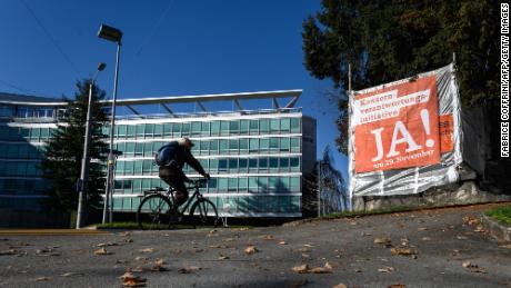 A man rides his bicycle on November 18, 2020, next to the headquarters of Swiss food giant Nestle and a campaign banner reading in German: &quot;Corporate responsibility initiative, Yes!&quot; ahead of a November 29, 2020 nationwide vote on a people&#39;s initiative to impose due diligence rules on Swiss-based firms active abroad. (Photo by Fabrice Coffrini/AFP/Getty Images)