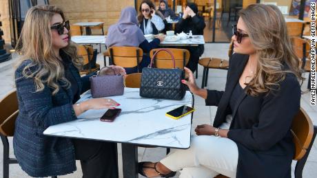 Saudi Mashael Aljaloud (L) and her friend Haifa Altwailai chat at a coffee shop in the Saudi capital Riyadh on November 19, 2020. - Saudi Arabia, the first Arab nation to host the G20, had planned for a grand summit that would showcase the ambitious modernisation drive of de-facto ruler Crown Prince Mohammed bin Salman but the coronavirus pandemic has dampened those hopes. In August last year, Saudi Arabia allowed women over the age of 21 to obtain passports and travel abroad without seeking the approval of their &quot;guardians&quot; -- fathers, husbands or other male relatives. The move ended a longstanding rule that prompted many extreme attempts by Saudi women to flee the kingdom. (Photo by FAYEZ NURELDINE / AFP) (Photo by FAYEZ NURELDINE/AFP via Getty Images)