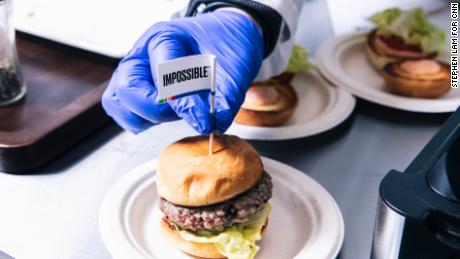 A technician places a flag toothpick into a burger with an Impossible burger patty at the test kitchen inside Impossible Foods headquarters in Redwood City, Calif. on Thursday, June 20, 2019.