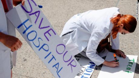 Dr. Angela Silverman makes a placard before joining a demonstration against the planned closure of Hahnemann University Hospital, at City Hall in Philadelphia, Thursday, June 27, 2019. The owner of hospital has announced it will close in September because of what the company calls &quot;continuing, unsustainable financial losses.&quot;(AP Photo/Matt Rourke)