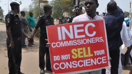 People hold signs to protest postponement of elections, as police officers hold hands to blocks protesters, on February 7, 2015 in Abuja. The six-week delay was announced on February 7, 2015 after security chiefs said the military needed more time to secure areas under the control of Boko Haram, the Islamist extremists who have seized swathes of northeastern Nigeria. Presidential and parliamentary elections will now be held on March 28 instead of February 14, said Attahiru Jega, chairman of the Independent National Electoral Commission (INEC). AFP PHOTO / STRINGER (Photo credit should read STRINGER/AFP/Getty Images)