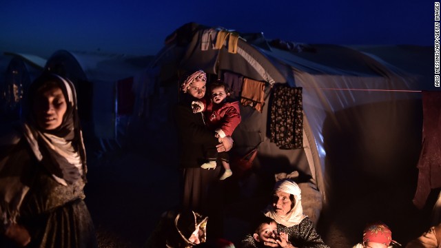 Syrian Kurdish refugees sit outside tents at a refugee camp in Suruc on November 11.