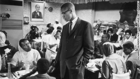 circa 1965:  Black nationalist and Muslim leader Malcolm X (1925 - 1965) talking to a woman inside Temple 7, a Halal restaurant patronized by black Muslims and situated on Lenox Avenue and 116th Street, Harlem, New York.  (Photo by Richard Saunders/Hulton Archive/Getty Images)