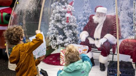 SEATTLE, WA - DECEMBER 06: Mateo Johnson, 6, and Neah Johnson, 3, share their Santa letters while visiting with Santa on December 6, 2020 in Seattle, Washington. Known as the Seattle Santa, he is usually booked for private events but is set up this year in a socially-distanced snow globe for public visits during the COVID-19 pandemic. (Photo by David Ryder/Getty Images)