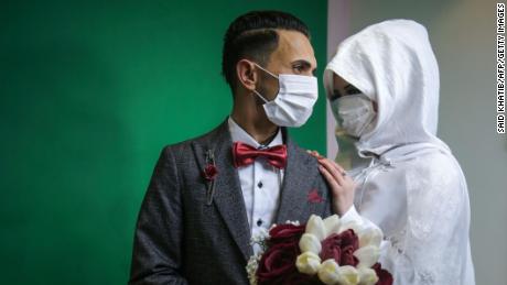 Palestinian groom Mohamed abu Daga and his bride Israa wear protective masks amid the COVID-19 epidemic, during a photoshoot at a studio before their wedding ceremony in Khan Yunis in the southern Gaza Strip, on March 23, 2020. - Authorities in Gaza confirmed on March 22 the first two cases of novel coronavirus, identifying them as Palestinians who had travelled to Pakistan and were being held in quarantine since their return, as the United Nations warned of potential disastrous outcomes to an outbreak given the high poverty rates and weak health system in the coastal strip, under Israeli blockade since 2007.