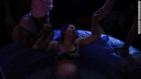 Nancy Pedroza, 27, who is pregnant, holds hands with Nichollette Jones, her doula, and Ryan Morgan, 30, her partner and the father to their unborn child, as she experiences contractions in a birthing tub, while laboring at the home of Pedroza&#39;s licensed midwife, Susan Taylor, where Pedroza plans to give birth, during the coronavirus disease (COVID-19) outbreak, in Fort Worth, Texas, U.S., April 7, 2020.  REUTERS/Callaghan O&#39;Hare     SEARCH &quot;CORONAVIRUS PREGNANCY&quot; FOR THIS STORY. SEARCH &quot;WIDER IMAGE&quot; FOR ALL STORIES. TPX IMAGES OF THE DAY