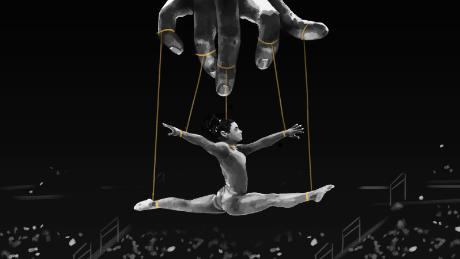 An illustration shows a gymnast hanging in midair. Her arms and legs are in a split position, tied by strings to fingers on a controlling hand above. The image is like that of a puppeteer and his puppet.