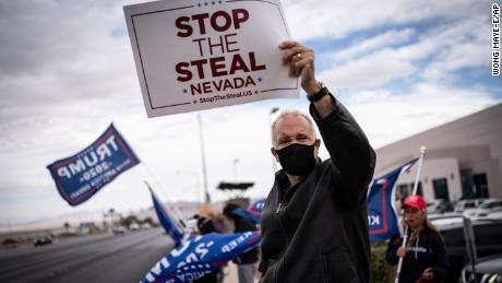 Supporters of President Donald Trump hold signs as they stand outside of the Clark County Elections Department in North Las Vegas, Nev. Saturday, Nov. 7, 2020. (AP Photo/Wong Maye-E)