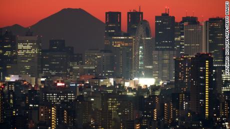 This picture taken on December 3, 2017 shows Japan&#39;s highest mountain, Mount Fuji at 3,776 meters (12,388 feet), seen behind skyscrapers in Tokyo&#39;s Shinjuku area during sunset.
Japan is growing twice as fast as previously estimated, official data showed on December 8, 2017, with the world&#39;s third-largest economy posting its longest string of gains in more than two decades. / AFP PHOTO / Kazuhiro NOGI        (Photo credit should read KAZUHIRO NOGI/AFP/Getty Images)