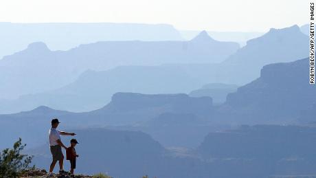 A father and son look out over the South Rim of the Grand Canyon, a detour off historic Route 66, in Arizona, 10 July 2003. More than four million people visit the Grand Canyon every year, most arriving by car. AFP PHOTO / Robyn BECK (Photo credit should read ROBYN BECK/AFP/Getty Images)