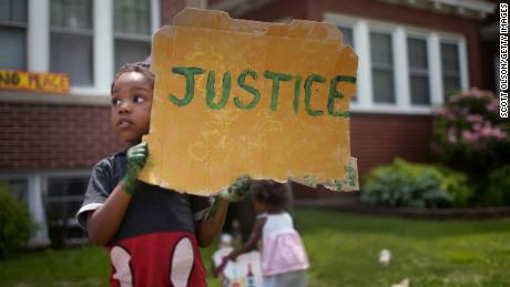 ST. PAUL, MINNESOTA  - JUNE 06: Xavier Brown shows his support as demonstrators march past his home while protesting police brutality following the death of George Floyd on June 06, 2020 in St. Paul, Minnesota. This is the 12th day of protests since Floyd died in nearby Minneapolis while in police custody on May 25. (Photo by Scott Olson/Getty Images)