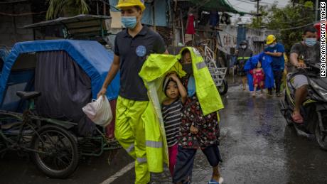 MANILA, PHILIPPINES - NOVEMBER 01: A rescue worker covers children in a raincoat as they evacuate before Typhoon Goni hits on November 1, 2020 in Manila, Philippines. Super Typhoon Goni, this year&#39;s most powerful storm in the world,  has made landfall in the Philippines with wind gusts of up to 165 miles per hour early Sunday. At least two people have been killed so far and hundreds of thousands have been evacuated ahead of the storm. (Photo by Ezra Acayan/Getty Images)
