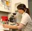 Young woman sitting by microscope, writing, side view